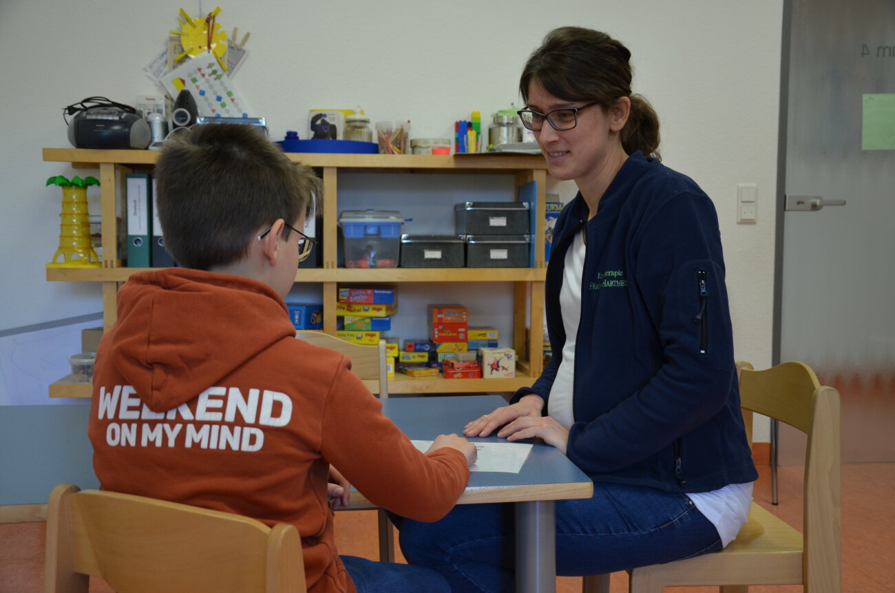 eine Mitarbeiterin hilft einem Kind beim Lernen mit dem IntraActPlus Konzept